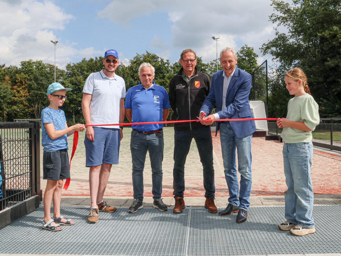 Wethouder Jan Uitslag knipt het lint door dat wordt vastgehouden door Tim Mensink en Tess Geerts (jeugdleden MHC Dalfsen). Verder vlnr.: voorzitters Maarten Mensink (MHC Dalfsen), Bert Visscher (ASC’62) en Dirk Mosterman (SV Dalfsen).  Foto Gemeente Dalfsen.